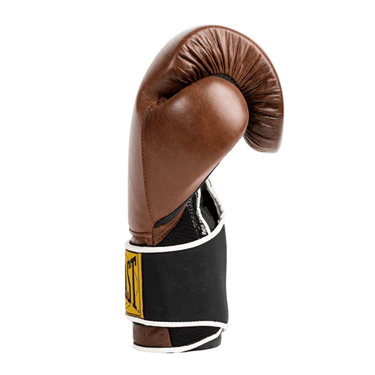 Afbeelding van de zijkant van een bruine Everlast 1910 Classic Training bokshandschoen, met de duim goed zichtbaar. De handschoen heeft een klassieke leren buitenkant en een zwarte polsband met het gele Everlast-logo en witte randafwerking. Het ontwerp combineert een vintage uitstraling met moderne ondersteuning en comfort voor de drager.