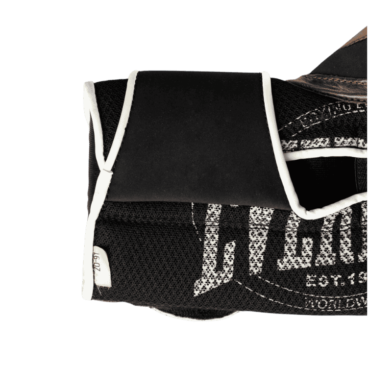 Close-up afbeelding van de polsband en binnenkant van een bruine Everlast 1910 Classic Training bokshandschoen. De afbeelding toont het zwarte mesh-materiaal met witte details en een gedeeltelijk zichtbaar Everlast-logo. De polsband is zwart met witte omranding en biedt stevige ondersteuning tijdens het dragen. Het ontwerp benadrukt zowel ventilatie als comfort.