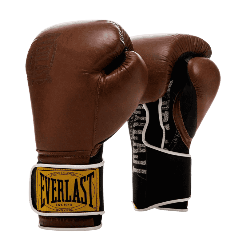 Afbeelding van Everlast 1910 Classic Training bokshandschoenen in bruin leer. De handschoenen hebben een vintage uitstraling met een gestikt Everlast-logo op de polsband in geel en zwart. De binnenkant van de handschoenen heeft een zwart-wit patroon en een klittenbandsluiting met witte randafwerking, wat zorgt voor een stevige en comfortabele pasvorm tijdens trainingen.