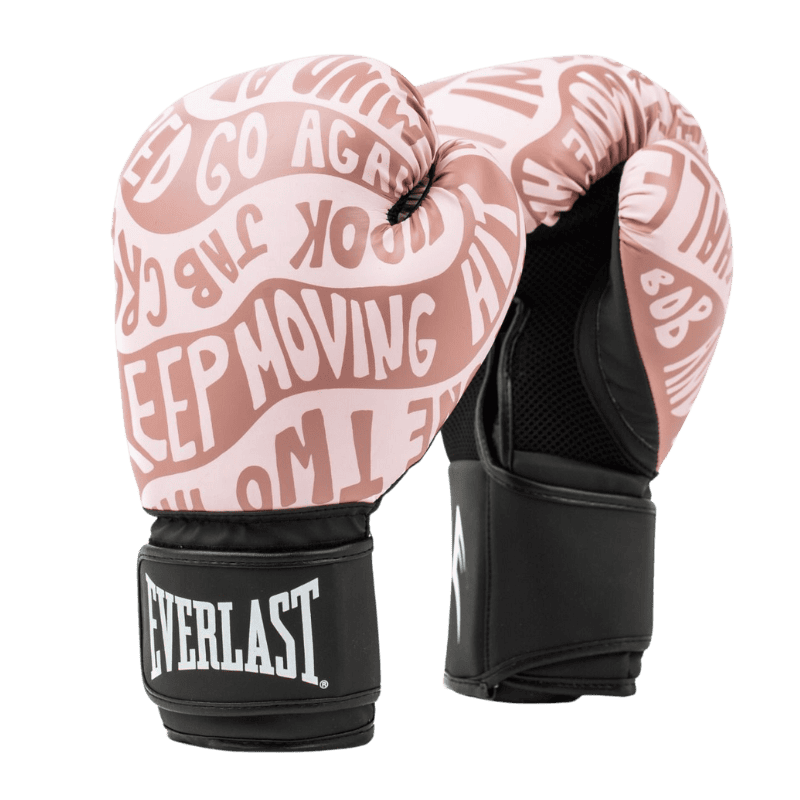 Een paar Everlast bokshandschoenen in roségoud uit de Spark Motivate-serie. De handschoenen hebben een opvallend ontwerp met motiverende woorden zoals 'Keep Moving,' 'Jab,' 'Hook,' en 'Go Again' in witte letters op het oppervlak. De polsband is zwart met een wit Everlast-logo, wat zorgt voor een stijlvol contrast