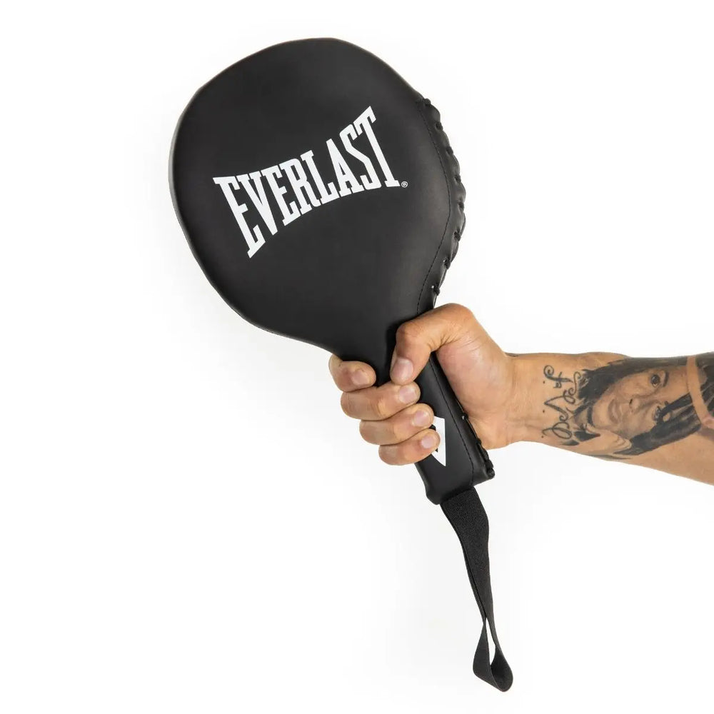 Hand met tatoeage houdt een zwarte Everlast trainingspaddle vast met witte logo-opdruk en polsband.