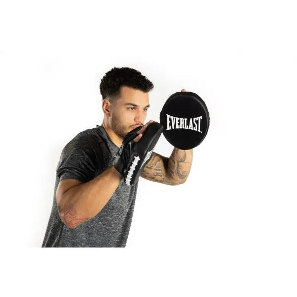 Man traint met zwarte Everlast punch mitts; hij houdt de pads omhoog om stoten op te vangen tijdens een boks- of kickbokstraining.