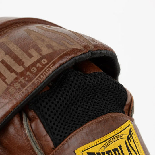 Close-up van de Everlast 1910 focus mitt in bruin leer met zwarte mesh binnenvoering en het gele Everlast-logo op de polsband