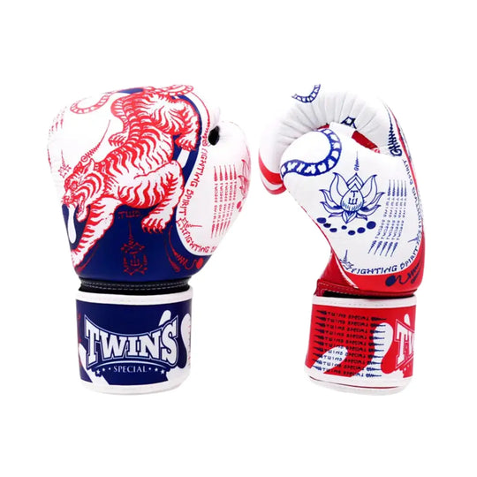 Detailaanzicht van de Twins Special bokshandschoenen met een krachtig rood, wit en blauw Yant-design. De dynamische tijgerprint en traditionele Thaise symbolen geven de handschoenen een unieke en authentieke uitstraling. De stevige klittenbandsluiting met duidelijke Twins-branding zorgt voor optimale polsondersteuning en een stabiele pasvorm tijdens intensieve trainingen.