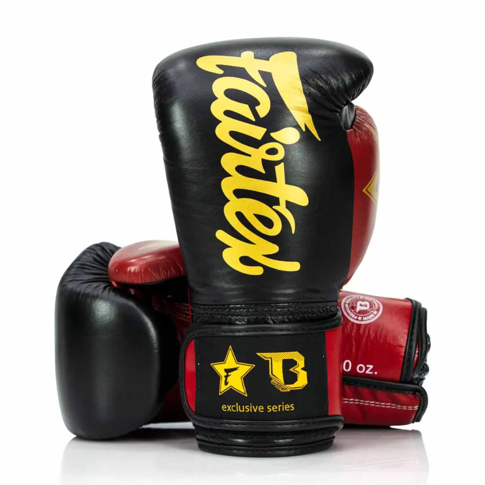 Zwarte en rode Fairtex x Booster bokshandschoenen met geel Fairtex-logo en polssluiting met “exclusive series”-opdruk.