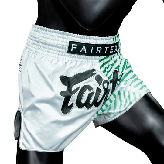 Fairtex Muay Thai shorts in wit met groene accenten en groot Fairtex-logo, gedragen door mannequin.