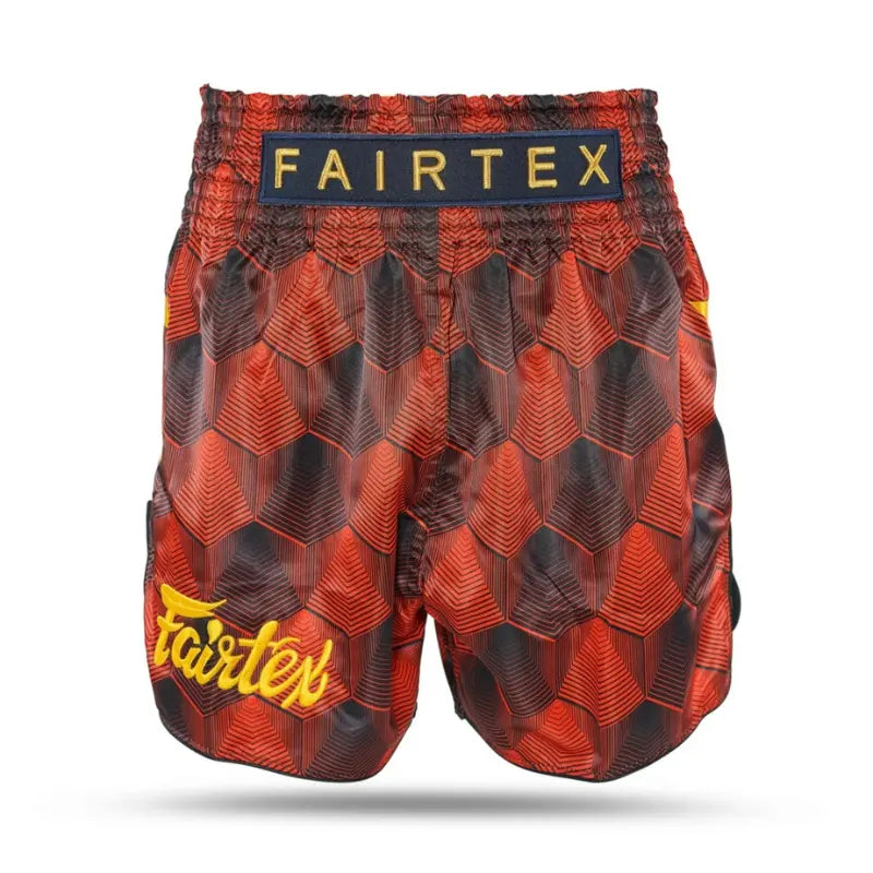 Fairtex kickboks short rood-zwart met geometrisch patroon, gele Fairtex-logo op de pijp en zwarte elastische tailleband met gouden merknaam.