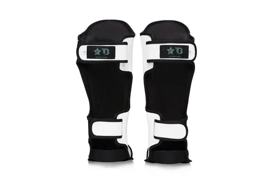 Achterkant van witte Fairtex scheenbeschermers met zwarte binnenvoering en dubbele klittenbandsluiting voor stevige bevestiging en draagcomfort.