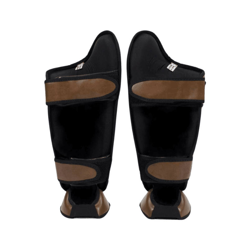 Fairtex scheenbeschermers in bruin leer met gele merkemblemen en klittenbandsluiting aan de achterkant.