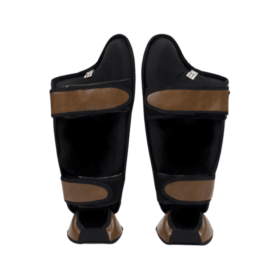 Fairtex scheenbeschermers in bruin leer met gele merkemblemen en klittenbandsluiting aan de achterkant.