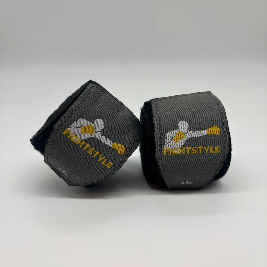 Zwarte Fightstyle bandages van 4.5 meter, deels uitgerold met zichtbaar logo, ideaal voor pols- en knokkelondersteuning tijdens bokstraining.