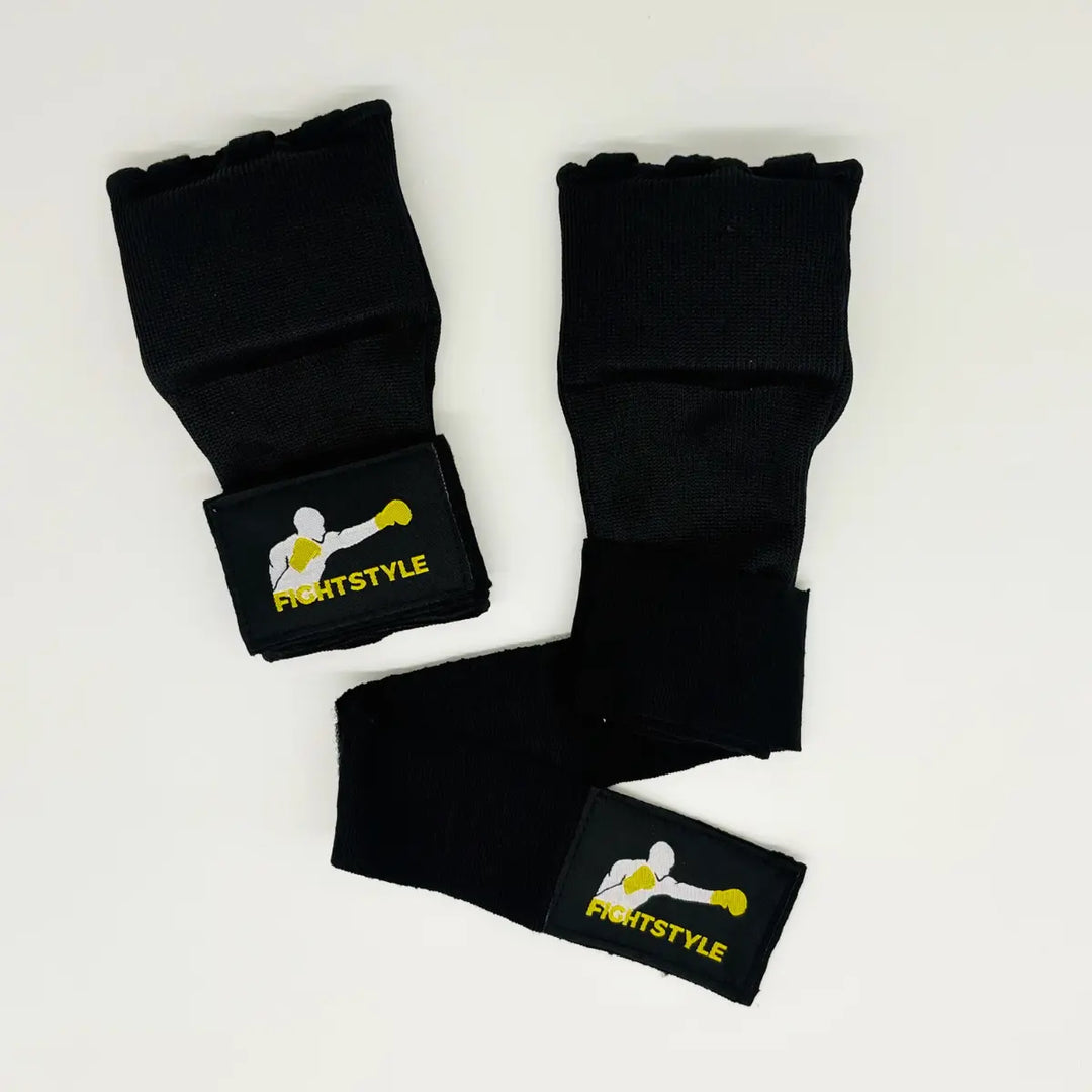 Bovenaanzicht van zwarte Fightstyle binnenhandschoenen met uitgestrekte polsbanden en gele bokser-logo op de labels.