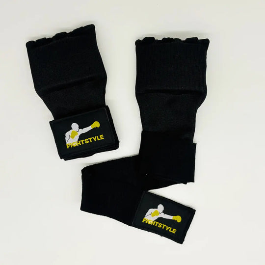 Bovenaanzicht van zwarte Fightstyle binnenhandschoenen met uitgestrekte polsbanden en gele bokser-logo op de labels.