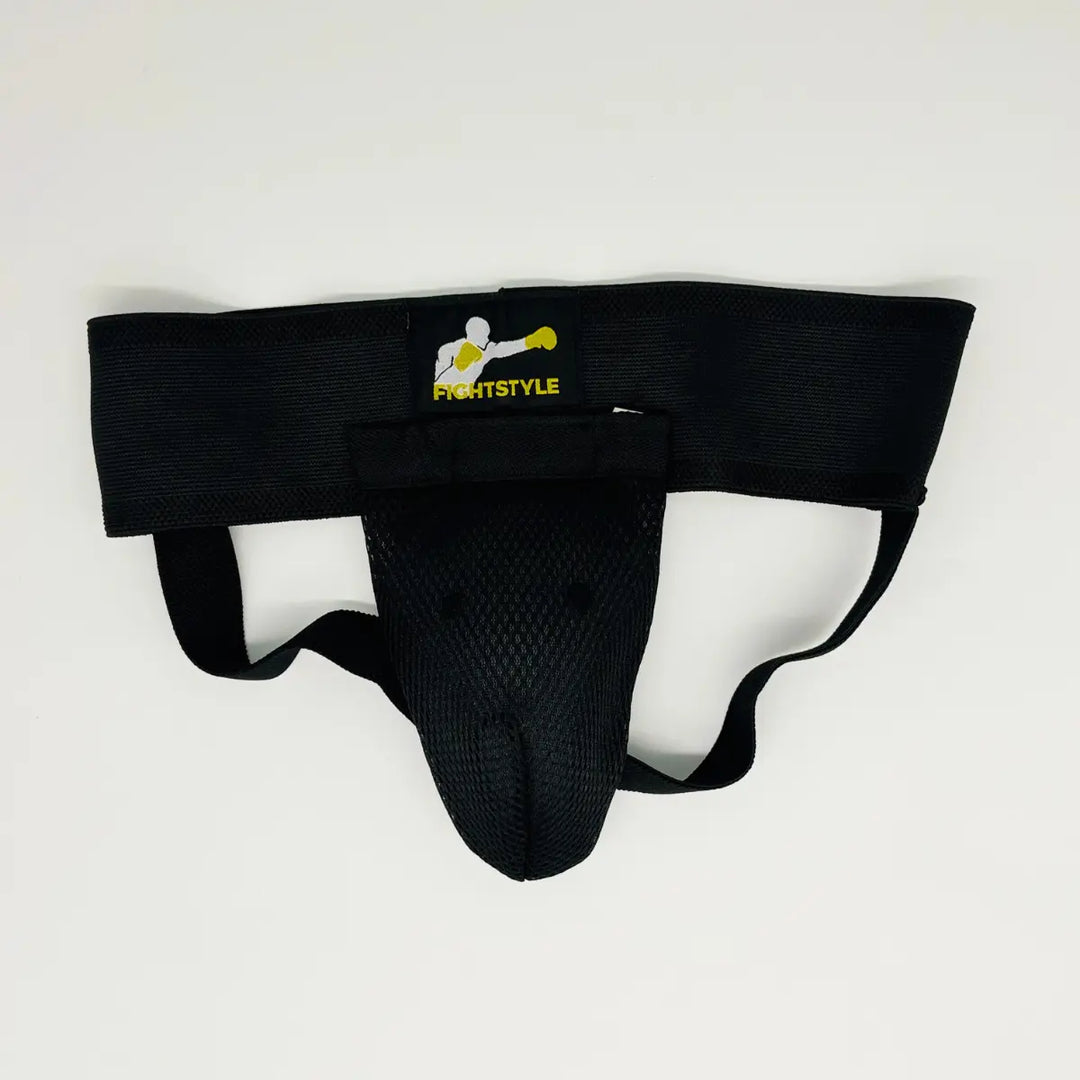 Zwarte Fightstyle kruisbeschermer met brede elastische band, mesh cup en geel Fightstyle-logo op de tailleband.