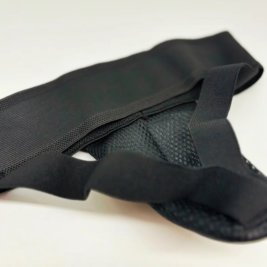 Close-up van zwarte Fightstyle kruisbeschermer met elastische band en geventileerde mesh binnenzijde.