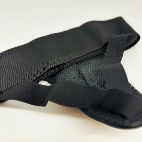 Close-up van zwarte Fightstyle kruisbeschermer met elastische band en geventileerde mesh binnenzijde.