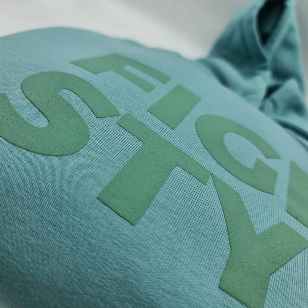 Close-up van het verhoogde Fightstyle-logo op de Teal Monstera hoodie. De zachte textuur en matte afwerking benadrukken de premium kwaliteit en stijlvolle afwerking van deze streetwear essential.