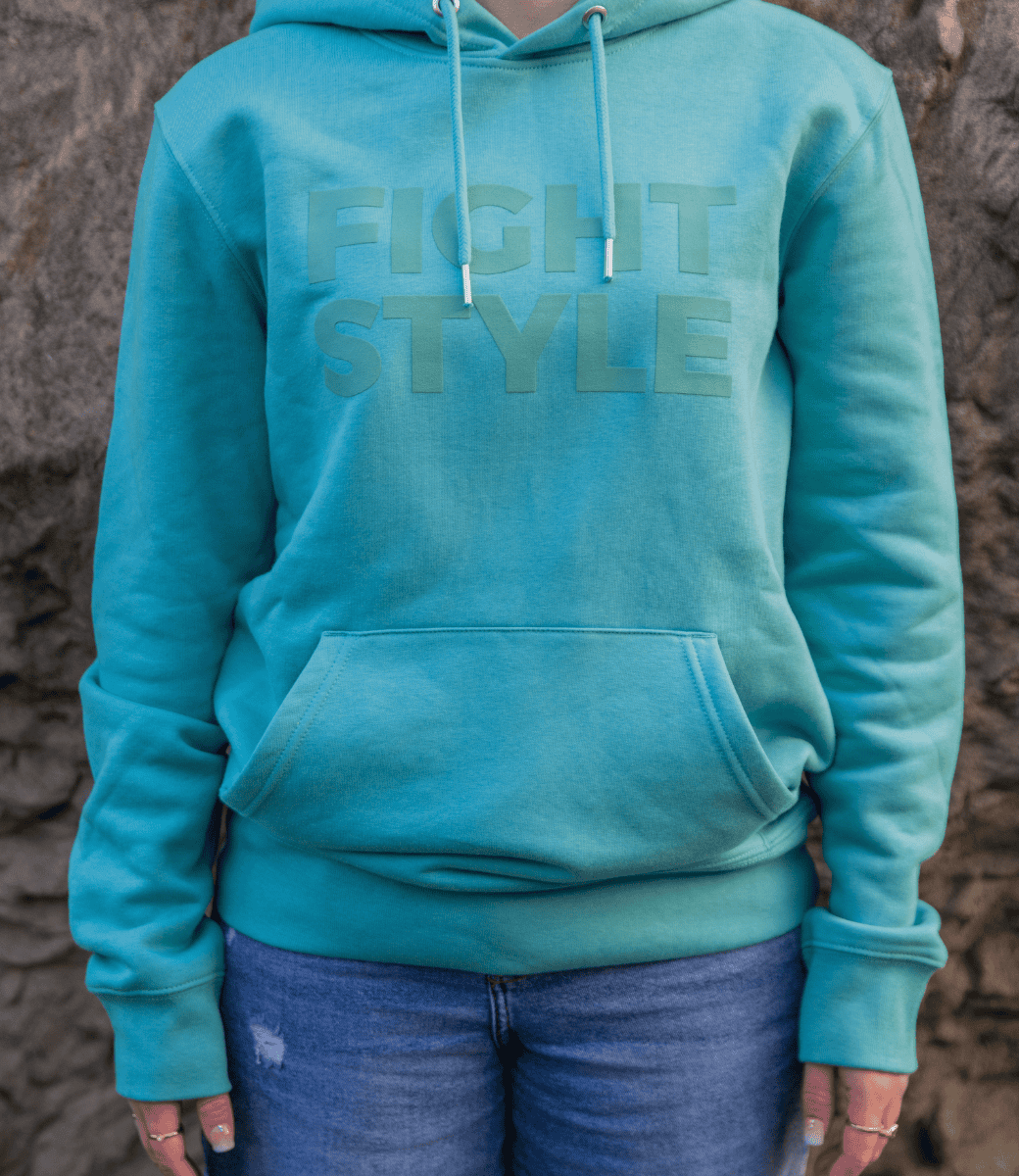 Close-up van de Fightstyle hoodie Teal Monstera met subtiel logo op de borst. De hoodie heeft een frisse teal kleur, zachte stof en kangoeroezak voor ultiem draagcomfort en een moderne streetwear look.