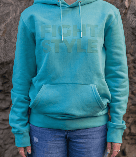 Close-up van de Fightstyle hoodie Teal Monstera met subtiel logo op de borst. De hoodie heeft een frisse teal kleur, zachte stof en kangoeroezak voor ultiem draagcomfort en een moderne streetwear look.