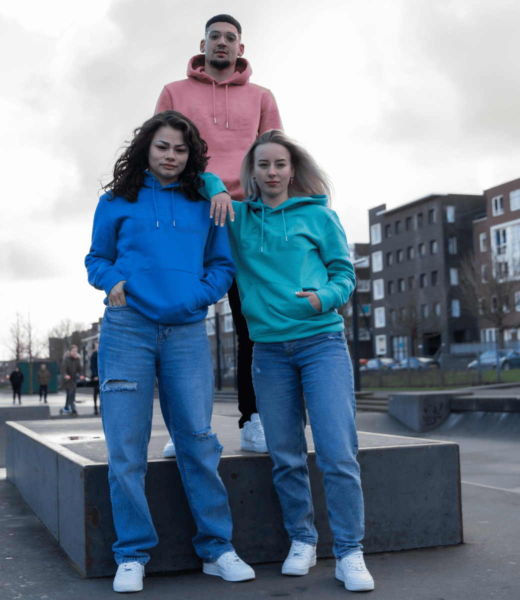 Drie modellen dragen Fightstyle hoodies in blauw, teal en koraalroze tijdens een fotoshoot in het skatepark. De hoodies hebben een moderne fit en een clean logo-design, perfect voor fighters die stijl en comfort willen combineren.
