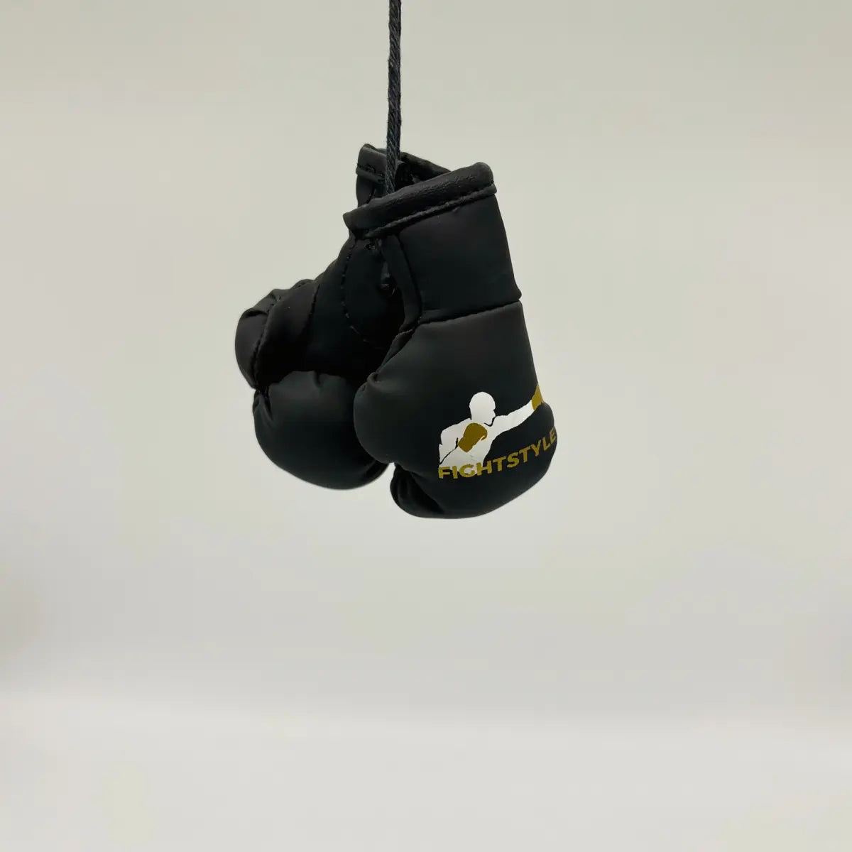 Zwarte Fightstyle mini bokshandschoenen aan een koord, gebruikt als decoratie of sleutelhanger met goud-wit logo.