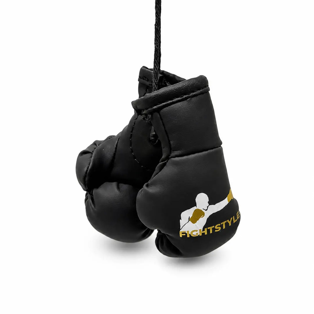 Zwarte mini bokshandschoenen van Fightstyle hangend aan een zwart koord. Het compacte ontwerp met geel-wit logo maakt ze geschikt als decoratie, accessoire of sportieve toevoeging voor boksers en kickboksers.