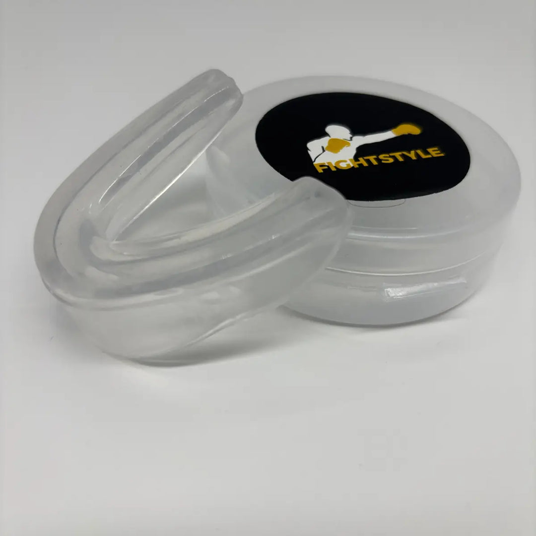 Detailfoto van de transparante Fightstyle mondbeschermer naast het opbergdoosje, ideaal voor bescherming tijdens boksen en kickboksen.