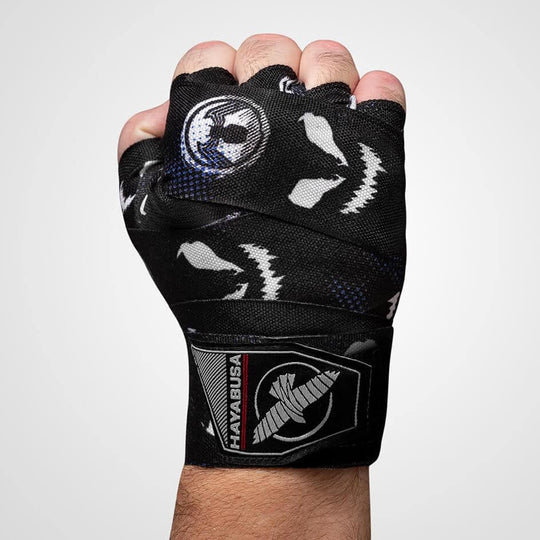 Close-up van een gebalde vuist met een zwarte en witte Hayabusa handbandage, versierd met het Symbiote patroon en het Hayabusa logo op de pols.