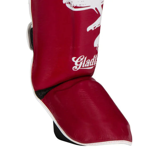 Close-up of Gladts shin guards in bordeaux red with integrated foot protection and reinforced padding. The ergonomic shape provides solid coverage for the shin and instep. Designed for comfort, protection, and durability during intensive kickboxing training.