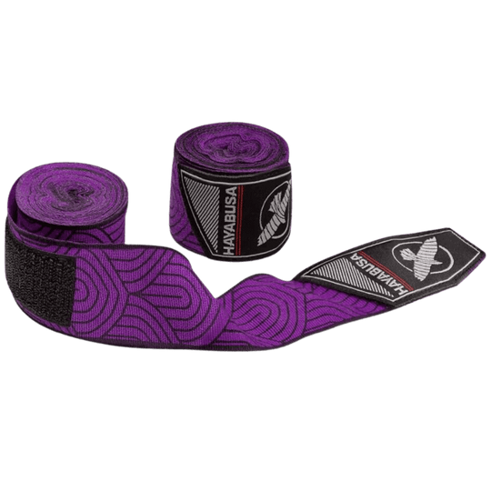 De Hayabusa Perfect Stretch Bandage Purple Lotus is deels uitgerold om het unieke paarse lotuspatroon te tonen, met het logo op de bandagesluiting zichtbaar.