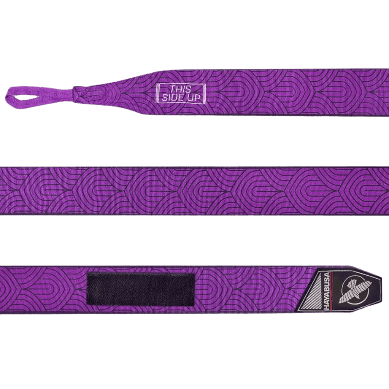 Een volledig uitgestrekte Hayabusa Perfect Stretch Bandage Purple Lotus met een herhalend lotuspatroon. Het bevat de tekst "THIS SIDE UP" aan het ene uiteinde en een zwart klittenbandstuk aan het andere uiteinde, naast het Hayabusa-logo.