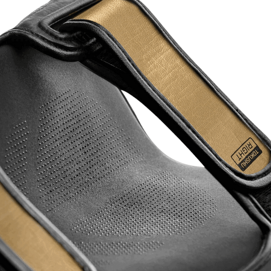 Detailopname van de binnenkant van een Hayabusa T3 Striking Scheenbeschermer in zwart en goud, waarbij het ademende materiaal en de voering benadrukt worden.