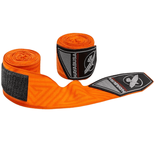 De oranje Hayabusa Perfect Stretch Bandages gedeeltelijk uitgerold, met het doolhofpatroon zichtbaar over de gehele lengte en het Hayabusa valk-logo op de bandagesluiting.
