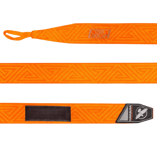Een volledig uitgestrekte Hayabusa Perfect Stretch Bandage in oranje, met het doolhofpatroon over de lengte en 'THIS SIDE UP' instructie aan het ene uiteinde en een zwart klittenbandstuk aan het andere, naast het logo.