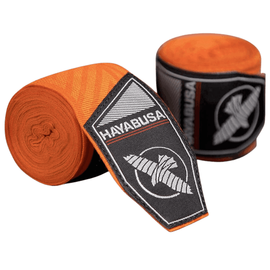 Een paar Hayabusa Perfect Stretch Bandages in de kleur oranje met een ingewikkeld doolhofpatroon, opgerold naast hun zwarte verpakking met het Hayabusa valk-logo in wit.