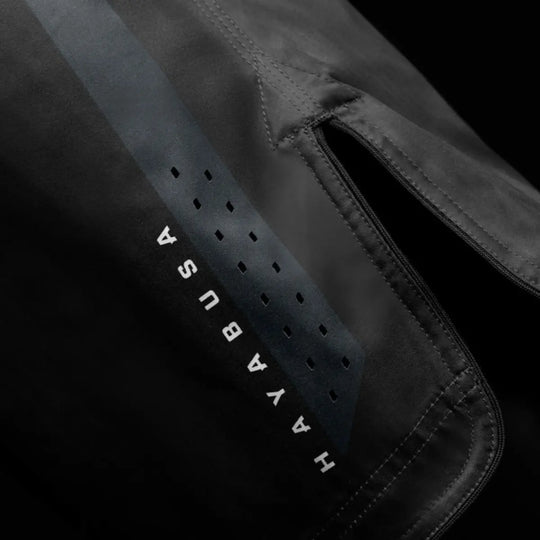 Close-up van zijkant met ventilatieperforaties, ritsopening en subtiel Hayabusa-logo.