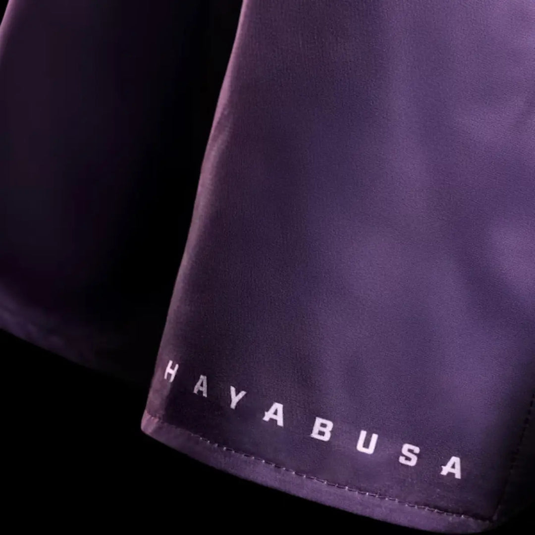 Close-up van paarse Hayabusa fightshorts met wit merklogo op de pijp, gemaakt voor duurzaamheid en comfort tijdens bokstraining.