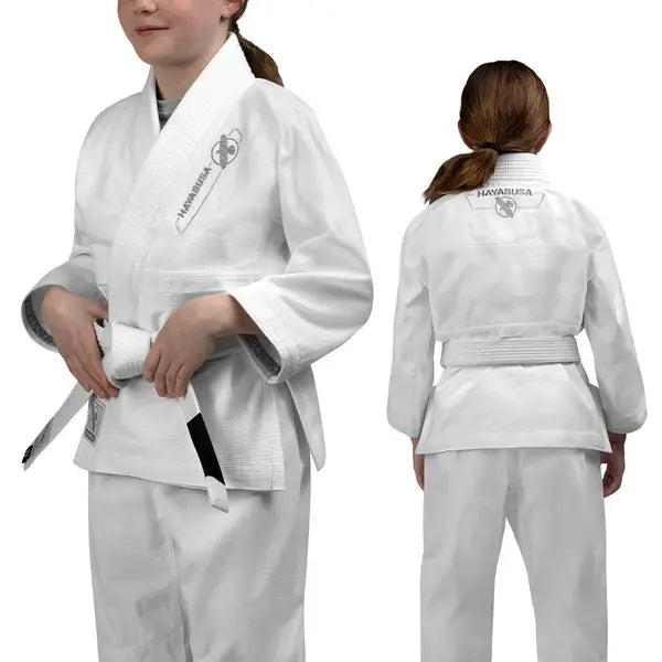 Jonge vechter in witte Hayabusa Essential Youth BJJ Gi met witte band, voor- en achteraanzicht van het lichte en ademende jiu-jitsu pak voor kinderen.