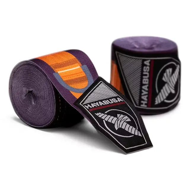 Uitgerolde paarse Hayabusa bandage met oranje accenten en zwart-wit Hayabusa logo, tweede rol bandage op de achtergrond.