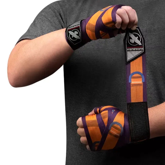 Man die paarse en oranje Hayabusa Batroc-bandages strak om beide handen wikkelt tijdens het inpakken van zijn handen.