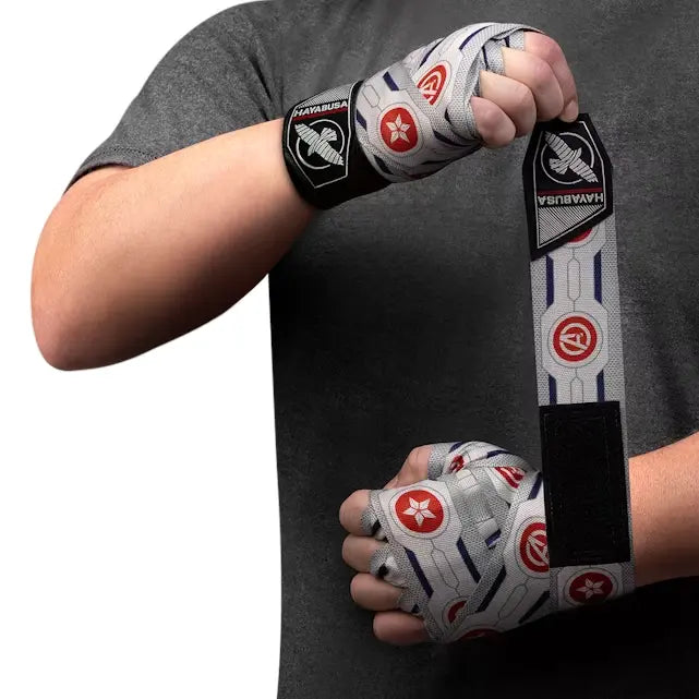 Grijze Hayabusa handwraps met rode en blauwe Falcon- en Avengers-logo’s, om de handen gewikkeld tijdens het inbinden, gedragen door sporter in grijs shirt.