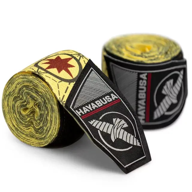 Op de afbeelding zie je een paar opgerolde Hayabusa handwraps met een gele basis en rode ster-accent, geïnspireerd op Captain Marvel. Op het label staat prominent het Hayabusa-logo in zwart, wit en rood.