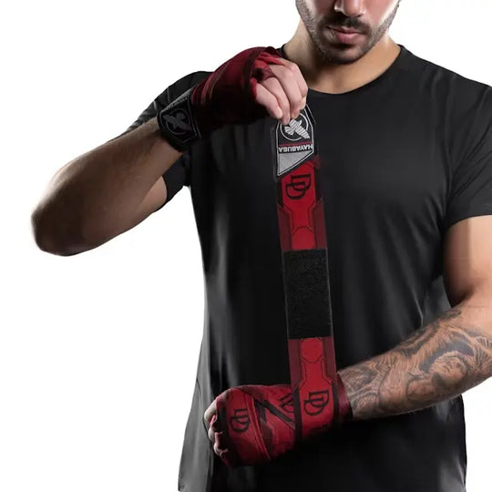 Man in zwart T-shirt wikkelt rode Hayabusa handwraps uit de Marvel Daredevil-collectie om zijn handen, met zichtbaar DD-logo en Hayabusa-label.