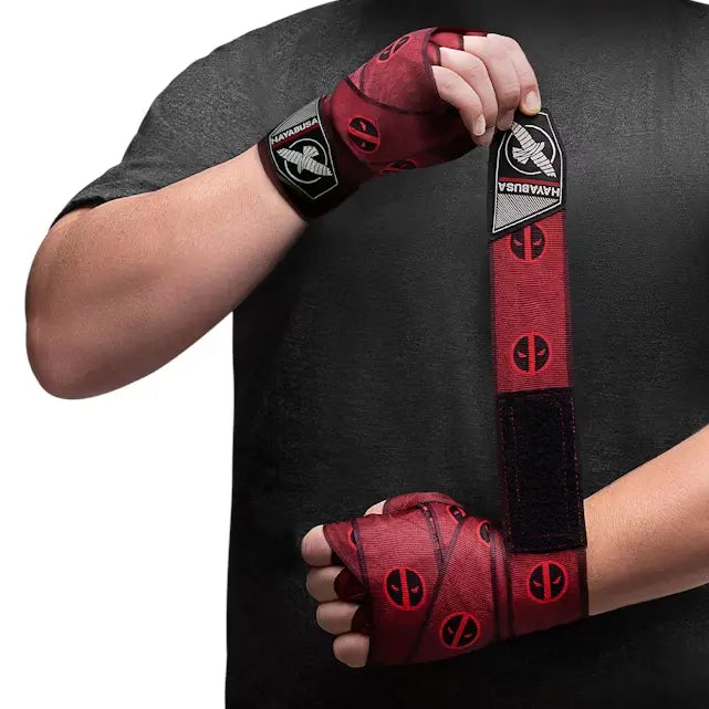 Man wikkelt Hayabusa Marvel Hero Elite Deadpool bandage om hand en pols, rood met zwarte Deadpool-logo’s en Hayabusa-logo.