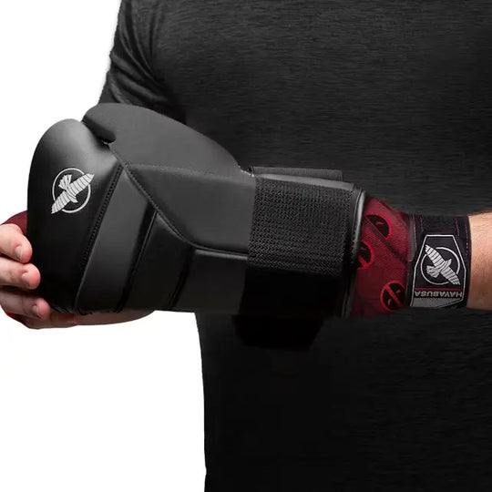 Man met zwart-grijze bokshandschoen en daaronder zichtbaar de Hayabusa Marvel Hero Elite Deadpool bandage in rood met zwarte logo’s.