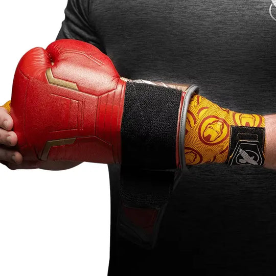 Hayabusa Iron Man bandages zichtbaar onder een rode bokshandschoen, met geel-rode Iron Man helm print en zwart Hayabusa-logo op de sluiting.