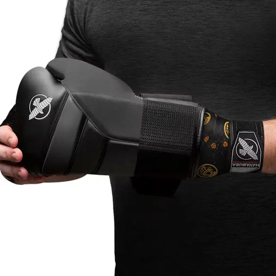 Persoon met zwarte Hayabusa bokshandschoen en eronder zichtbaar de zwarte Hayabusa Thanos bandage met gele Infinity Gauntlet en Infinity Stones details.