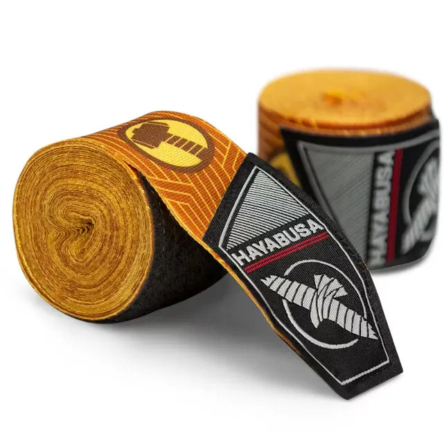 Gele Hayabusa bandages met zwart-wit logo en Thor-hamer symbool op de uiteinden, opgerold en gepresenteerd tegen witte achtergrond.