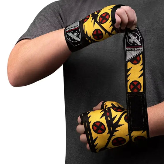 Persoon wikkelt Hayabusa Wolverine bandage met geel-zwart design en X-Men logo’s om de hand, zichtbaar Hayabusa polslabel.
