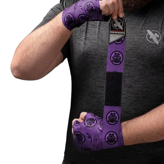 Man wikkelt paarse Hayabusa Marvel Hero Elite bandage om zijn hand, met zichtbaar Hayabusa logo en patroon.